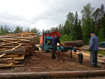Mökille lautaa sahaamassa. Mökki-isäntä Reijo tarkkailee tilannetta